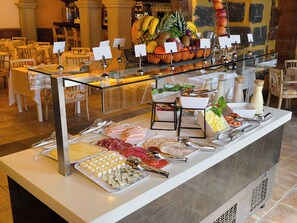 Ein Buffet mit verschiedenen Speisen, darunter Fleisch, Käse und Obst.