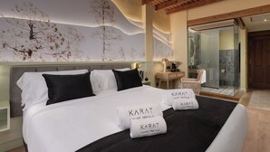 Habitació d'hotel moderna amb un llit gran, zona de dutxa de vidre i un mural únic a la paret.