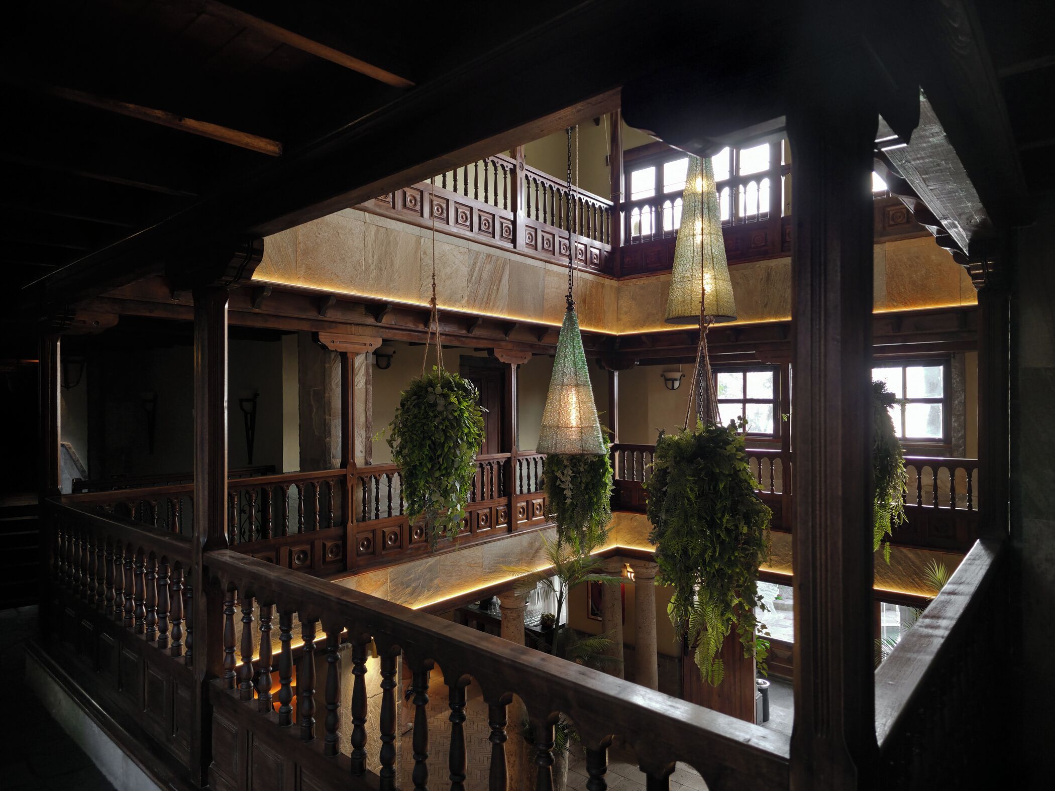 Un intérieur à plusieurs niveaux, agrémenté de rampes en bois et de plantes suspendues.