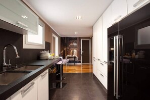 A modern kitchen with a black countertop, stainless steel appliances, and a view into a dining area. - AMAZING Plaza Catalunya & Paseo de Gracia (08007 Barcelona)