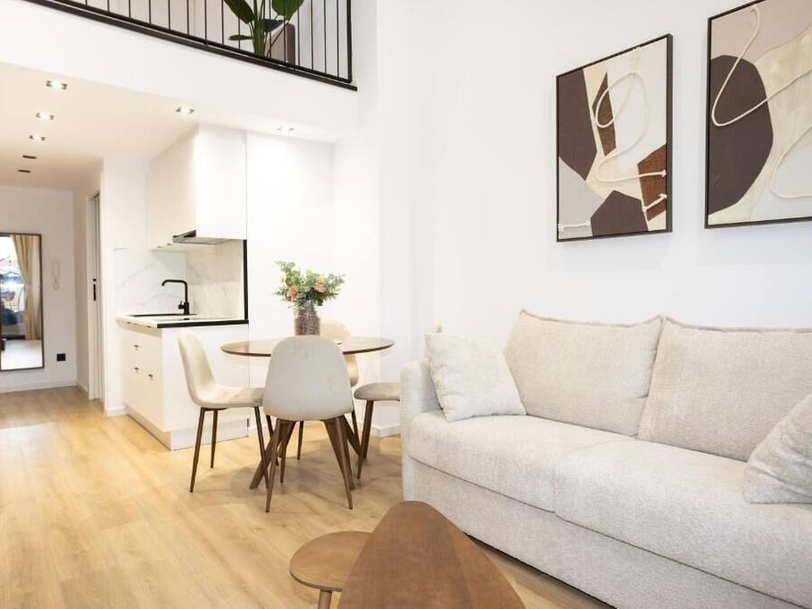 Una sala de estar moderna con un sofá, un comedor con sillas, una cocina y arte abstracto en la pared.