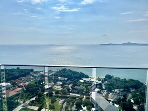 Un balcón con vistas a una zona costera, con edificios y vegetación.