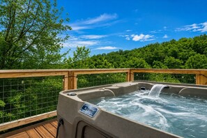 A hot tub on a wooden deck with a wire fence, surrounded by lush greenery. - Smoky Arrow | Hot Tub • Game Room • 3 min to Dollywood (Sevierville)