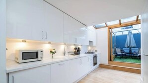 Una cocina moderna con armarios blancos, un microondas y un comedor con mesa y sillas.