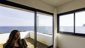 Une pièce dotée de grandes fenêtres donnant sur une plage et la mer.