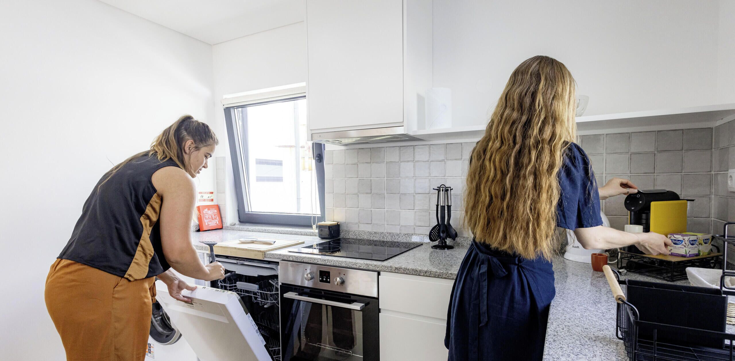Une cuisine moderne avec des meubles blancs, une fenêtre et un plan de travail sur lequel on trouve divers appareils et ustensiles.
