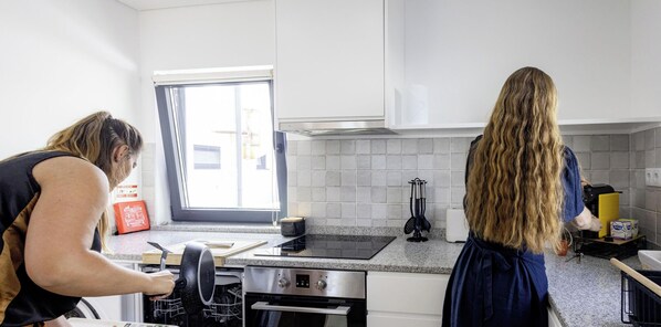 Eine moderne Küche mit weißen Schränken, einem Edelstahlbackofen und einem Fenster, das für natürliches Licht sorgt.