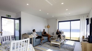 Un salon moderne avec un canapé, une table basse et un coin repas avec une table mise pour deux personnes.