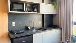Eine kleine Küche mit Mikrowelle, Kaffeemaschine und Spüle.