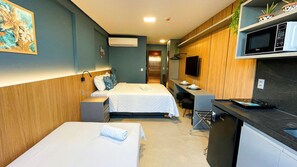 Habitación de hotel con dos camas, kitchenette, televisión de pantalla plana y un pequeño comedor.