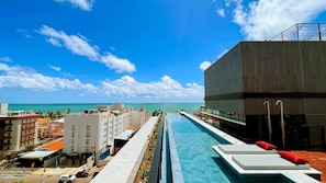 Una piscina con vistas al océano, un edificio moderno y un aparcamiento.