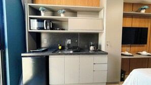 A compact kitchenette with a microwave, coffee maker, and a small refrigerator. - Condomínio Acqua Tambaú - By Almare (João Pessoa)