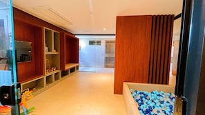 Un pasillo con estanterías de madera, un banco y una piscina de pelotas.