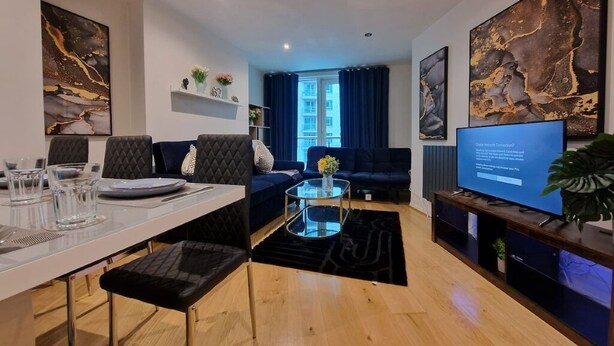 Ett modernt vardagsrum med en matplats, en soffa, en tv och konstverk på väggarna.
