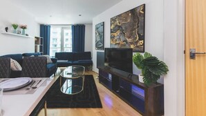 Ett modernt vardagsrum med en soffa, ett soffbord, en tv och konstverk på väggen.