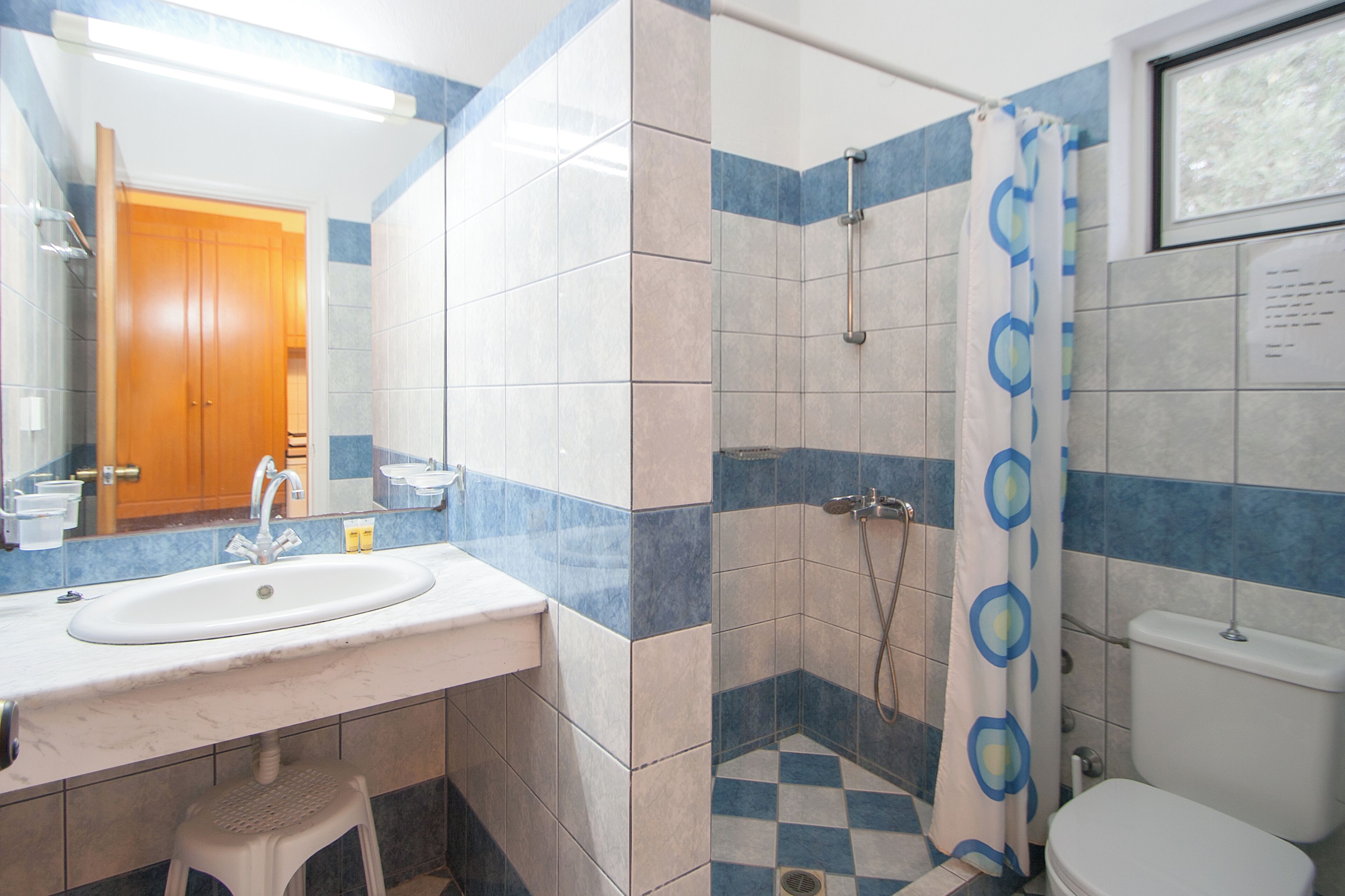 Une salle de bain équipée d’un lavabo, d’un miroir, d’une douche et de toilettes.