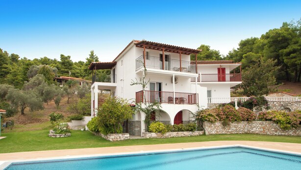 Une maison à deux étages avec une piscine en premier plan.