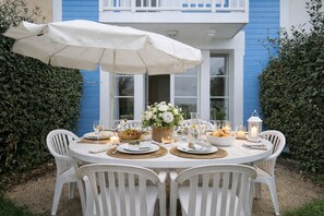 A round outdoor dining table set with white chairs, a white umbrella, and various dishes and drinks. - Holiday home for 6 people, Port de Bourgenay (Talmont-Saint-Hilaire)