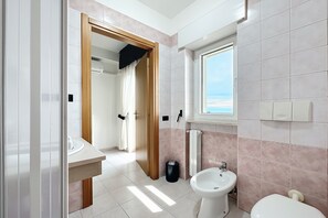 A bathroom with a toilet, sink, and window. - Bright B&B with Sea View Balcony - 102 - Santangelo - Pool (Monte Sant'Angelo)