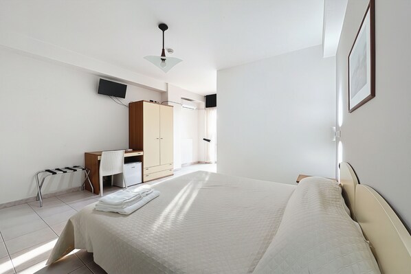 A bedroom with a bed, a desk, a chair, a radiator, and a TV mounted on the wall. - Bright B&B with Sea View Balcony - 102 - Santangelo - Pool (Monte Sant'Angelo)