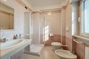 Un baño con ducha, inodoro, lavamanos y espejo.