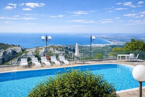 A swimming pool with lounge chairs and a view of the sea.
