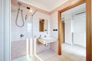 Un bagno moderno con doccia, lavandino e specchio.