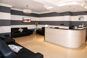 A modern hotel lobby with a black leather sofa, a curved reception desk, and a chandelier. - Bright B&B with Sea View Balcony - 105 - Santangelo - Pool (Monte Sant'Angelo)