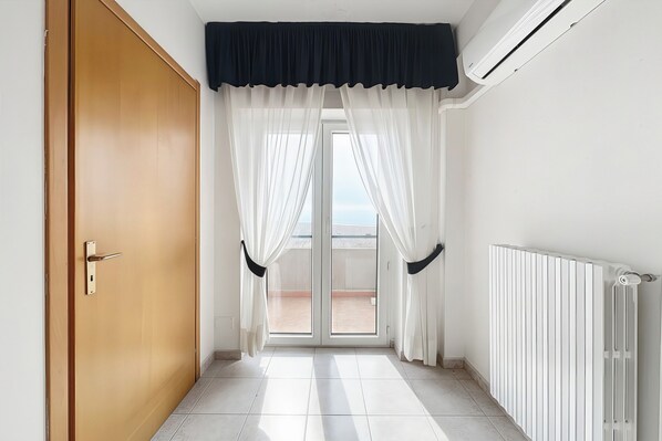 A hallway with a sliding door, a radiator, and a view through a glass door to an outdoor area. - Bright B&B with Sea View Balcony - 105 - Santangelo - Pool (Monte Sant'Angelo)