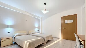 A room with two beds, a wooden door, a desk, and a chair. - B&B with Window - 106 - Santangelo - Pool (Monte Sant'Angelo)