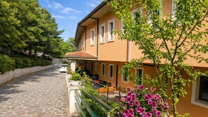 A building with a stone-paved street, a balcony with outdoor seating, and a potted plant with flowers. - B&B with Window - 107 - Santangelo - Pool (Monte Sant'Angelo)