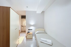 Ein Schlafzimmer mit Bett, Nachttisch, Kleiderschrank und einem Beistelltisch mit Lampe.