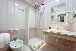 Ein Badezimmer mit Dusche, Bidet, Waschbecken und Spiegel.