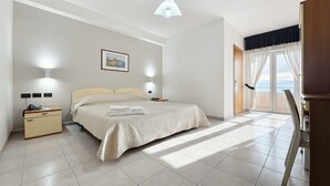 A bedroom with a bed, bedside tables, a nightstand, a chair, a desk, a window with curtains, and a view of the sea. - Bright B&B with Sea View Balcony - 225 - Santangelo - Pool (Monte Sant'Angelo)