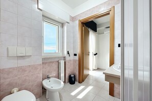 Un bagno con toilette, bidet, lavandino e finestra.