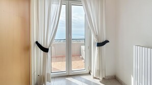 A room with a sliding glass door leading to a balcony with a view of the sea. - Bright B&B with Sea View Balcony - 225 - Santangelo - Pool (Monte Sant'Angelo)