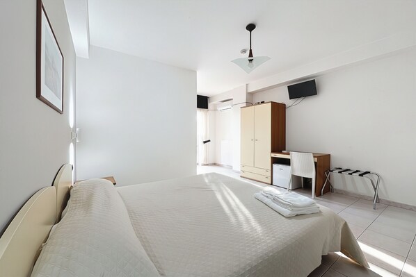 A bedroom with a bed, a desk, a chair, a wardrobe, and a television. - Bright B&B with Sea View Balcony - 225 - Santangelo - Pool (Monte Sant'Angelo)