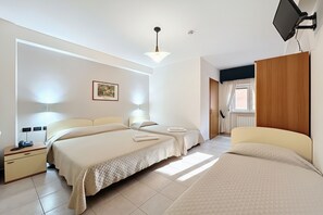 Habitación de hotel con dos camas, una mesita de noche, una lámpara, un cuadro en la pared y una ventana con cortinas.