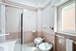 Un baño con ducha, inodoro, lavabo y ventana.