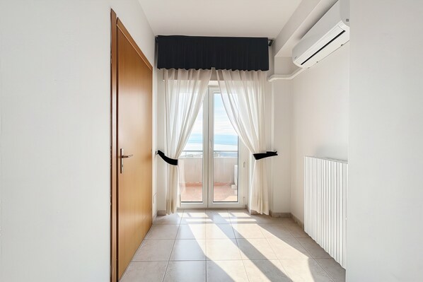 A hallway with a sliding glass door leading to a balcony, a radiator, and a ceiling-mounted air conditioner. - Bright B&B with Sea View Balcony - 227 - Santangelo Hotel - Pool (Monte Sant'Angelo)