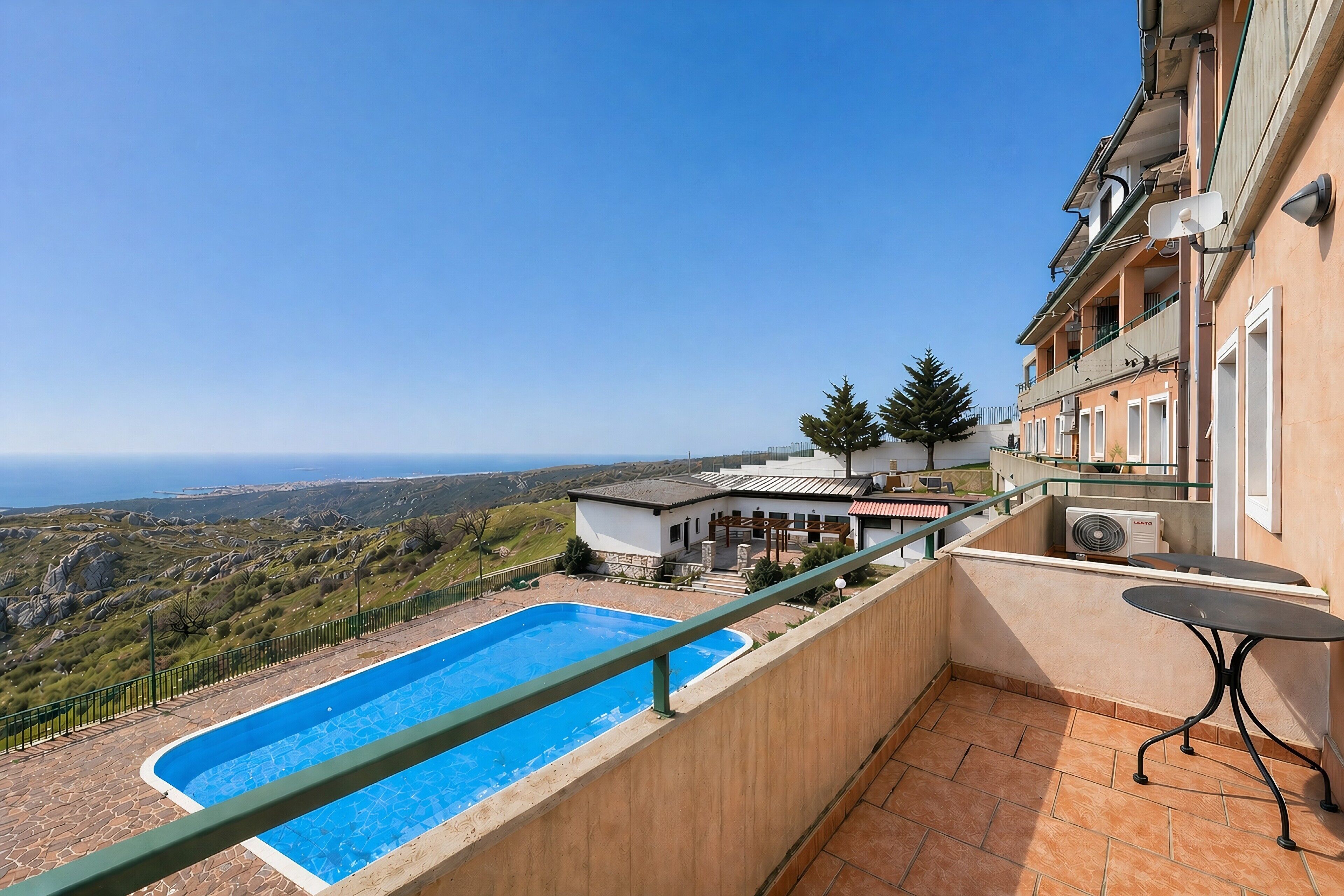 Ein Pool auf dem Dach mit Blick aufs Meer, ein Balkon mit Tisch und ein Gebäude mit Balkon.
