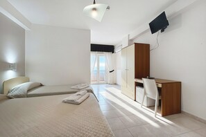 Camera d'albergo con due letti, una scrivania, una sedia, una televisione e vista sull'esterno.