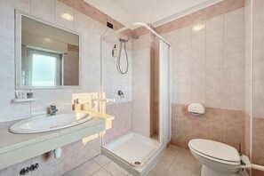 Un bagno con doccia, wc, lavandino e specchio.