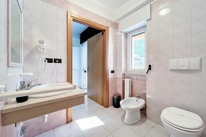 Ein Badezimmer mit Waschbecken, Spiegel, Handtuchhalter, Bidet, Toilette und einem Föhn.