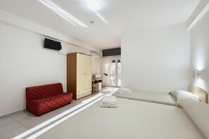 Ein Hotelzimmer mit einer Couch, einem Bett, einem Kleiderschrank, einem Schreibtisch und einem Fernseher.