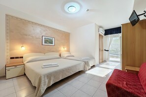 Et hotelværelse med to senge, et fjernsyn, en loftlampe og et vindue med gardiner.