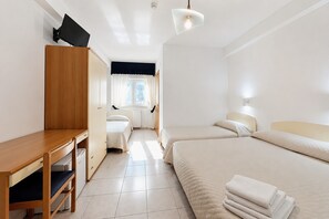 A hotel room with a wooden desk, two beds, a window with curtains, a radiator, and a ceiling light. - B&B with Window - 232 - Santangelo - Pool (Monte Sant'Angelo)