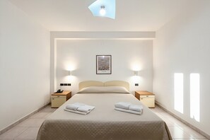 A hotel room with a bed, bedside tables, a nightstand, a framed picture on the wall, and a ceiling light fixture. - B&B with Window - 231 - Santangelo - Pool (Monte Sant'Angelo)