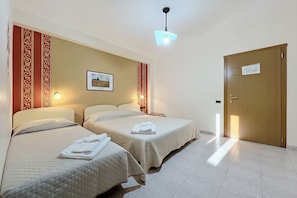 Ein Hotelzimmer mit zwei Betten, einer Holztür und einem gerahmten Bild an der Wand.