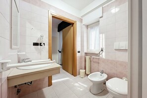 Ein modernes Badezimmer mit Waschbecken, Toilette, Bidet und Duschbereich.